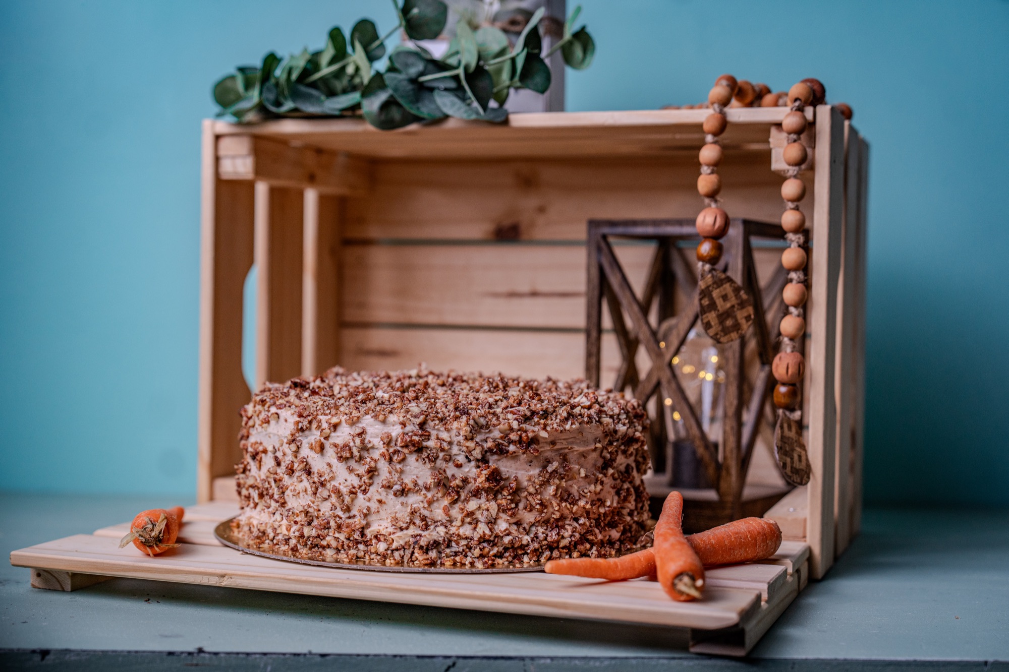 Carrot cake finished with toasted pecans, styled on a wooden crate
