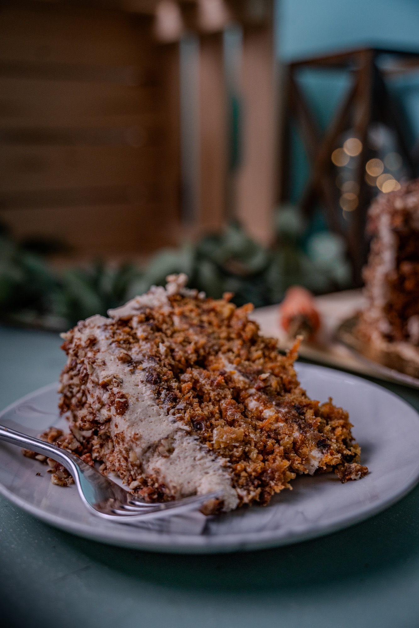 Slice of carrot cake plated with a dusting of toasted pecans