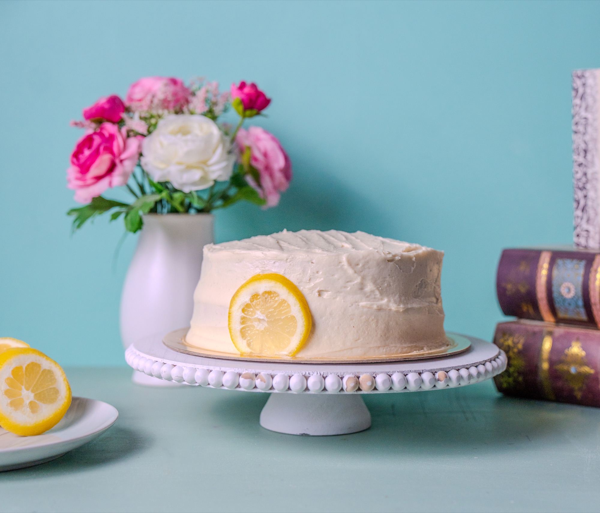 Lemon cake with a citrus slice garnish, styled with fresh roses